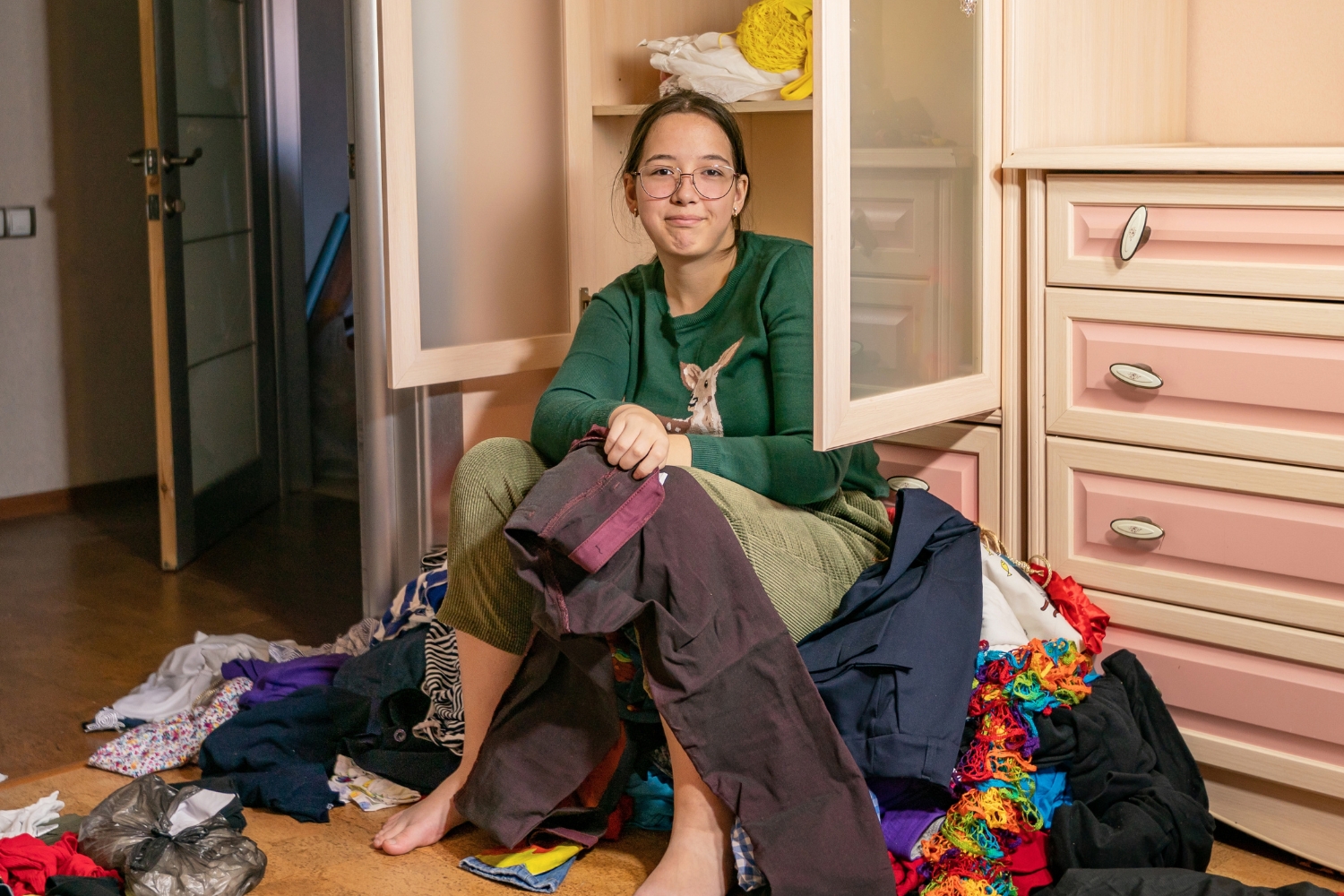 woman sitting on pile of clothes from decluttering before moving