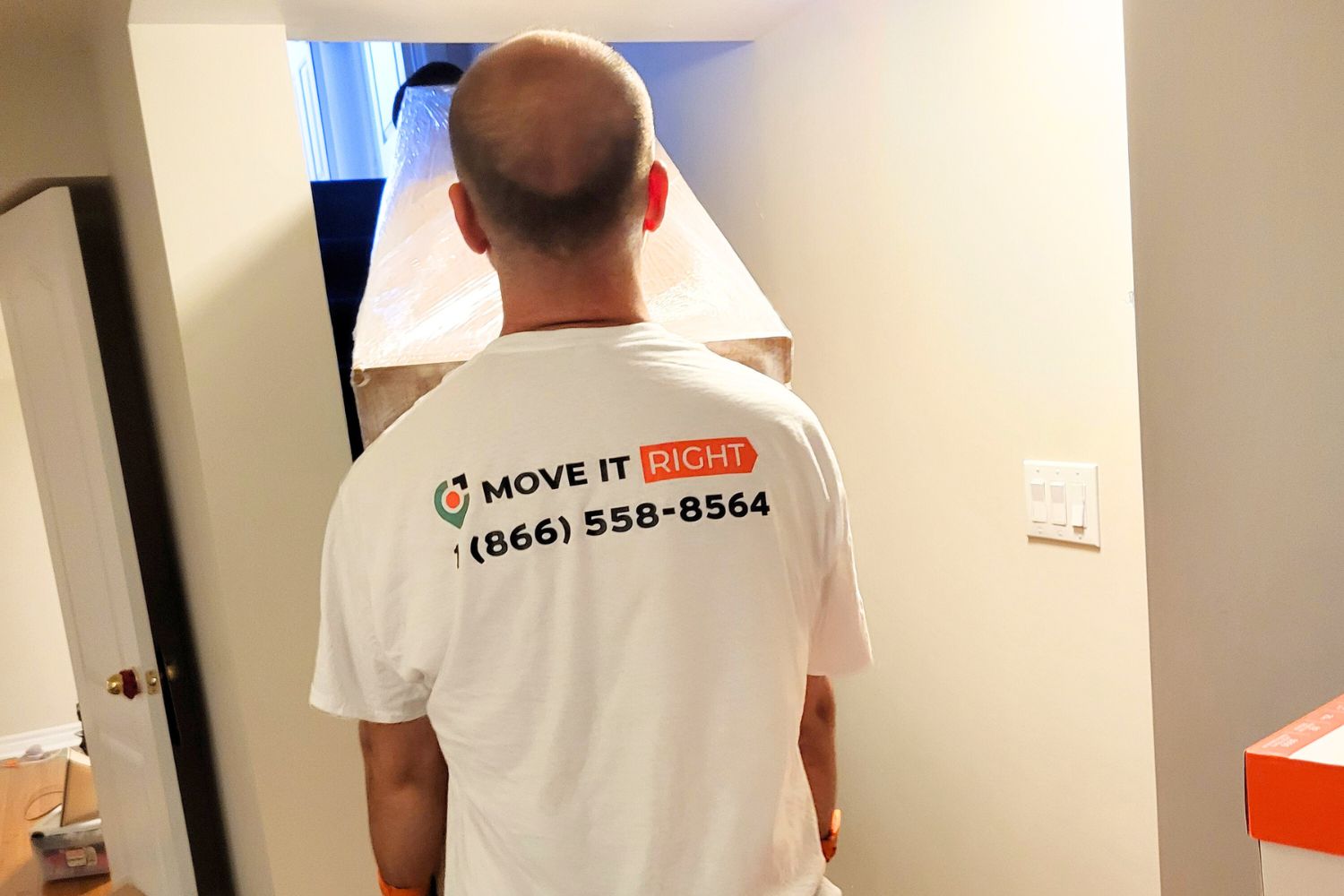 movers carrying box threw hallway